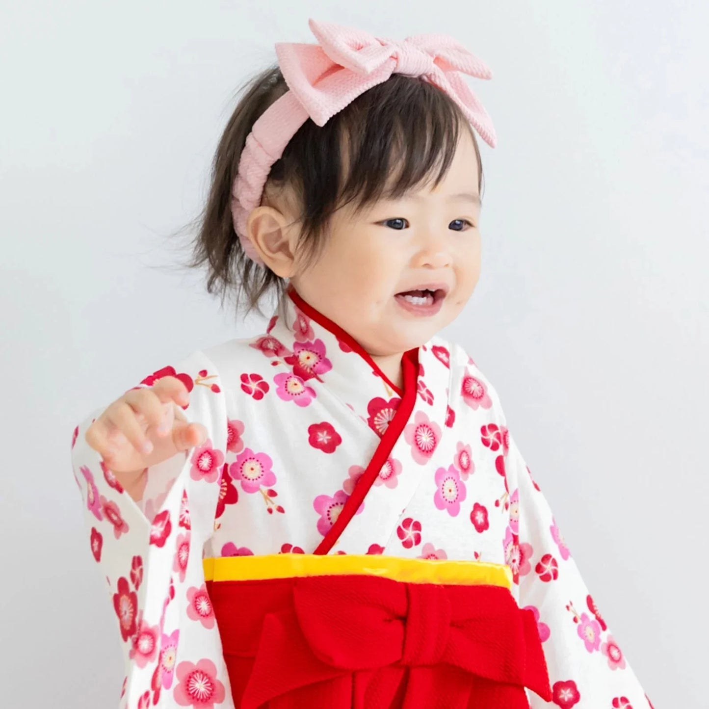 寶寶穿著紅色梅花和服連身衣進行新年或節慶拍照的可愛造型。