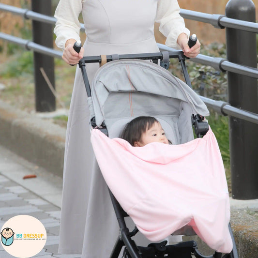 寶寶穿著粉紅色斗篷在戶外散步的可愛造型照。